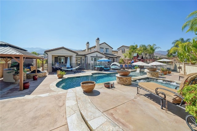 view of pool featuring pool water feature, a patio, a mountain view, and a gazebo