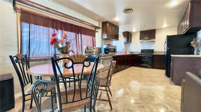 kitchen with dark brown cabinets, wall chimney range hood, light tile floors, and black appliances