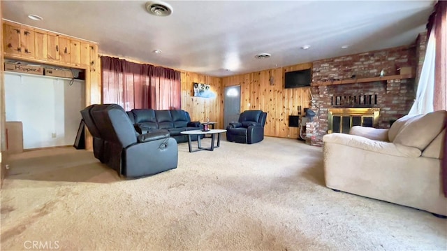 living room with carpet flooring, wood walls, brick wall, and a brick fireplace