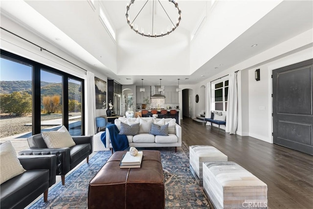 living room with a high ceiling, dark hardwood / wood-style floors, and an inviting chandelier