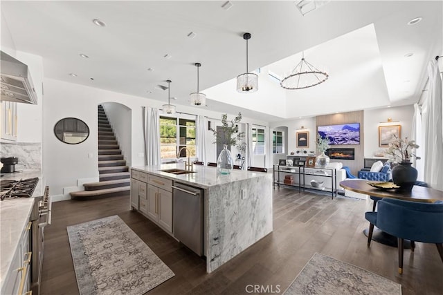 kitchen featuring light stone countertops, pendant lighting, appliances with stainless steel finishes, an island with sink, and sink