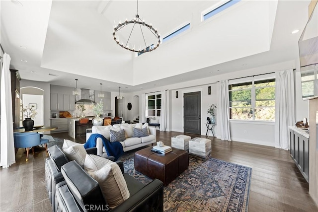 living room featuring a high ceiling, an inviting chandelier, and dark hardwood / wood-style flooring