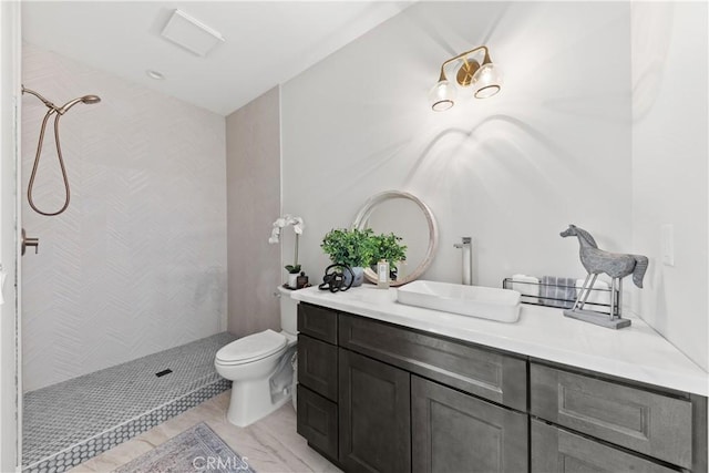 bathroom featuring tiled shower, toilet, and vanity