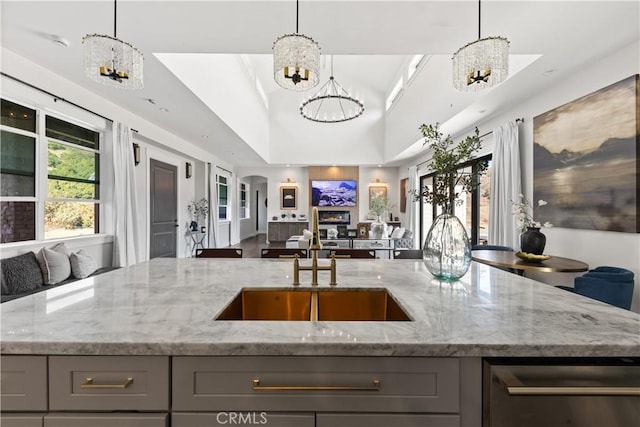 kitchen featuring hanging light fixtures, sink, light stone counters, gray cabinets, and an inviting chandelier