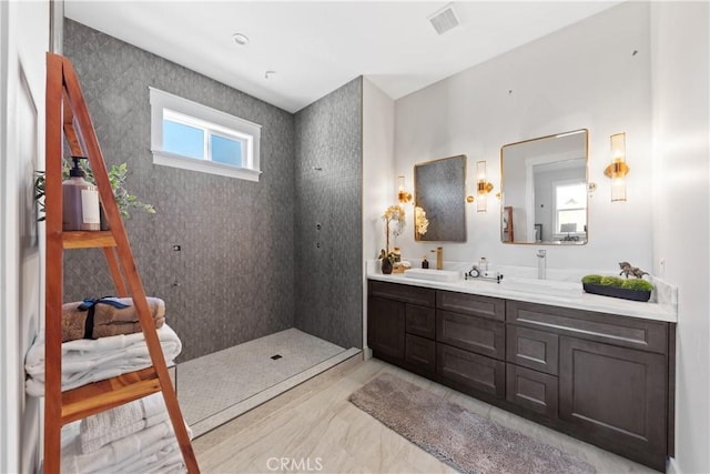 bathroom with tiled shower and vanity