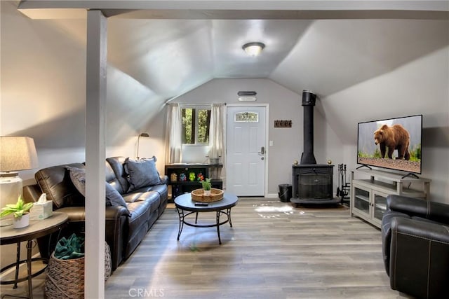 living room featuring a wood stove, light hardwood / wood-style floors, and lofted ceiling