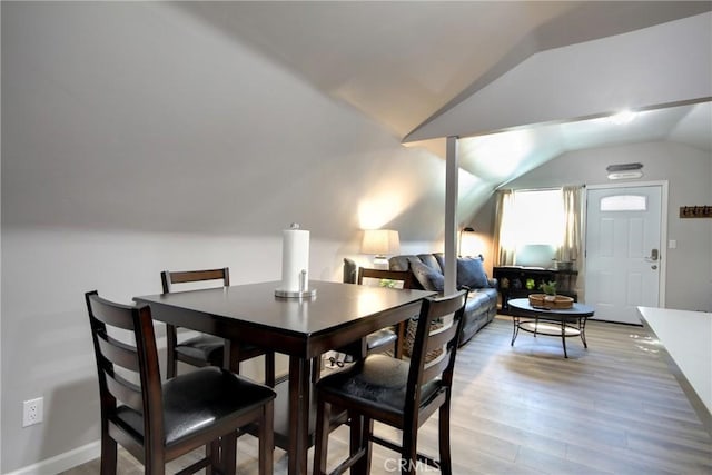 dining room featuring lofted ceiling and light hardwood / wood-style flooring