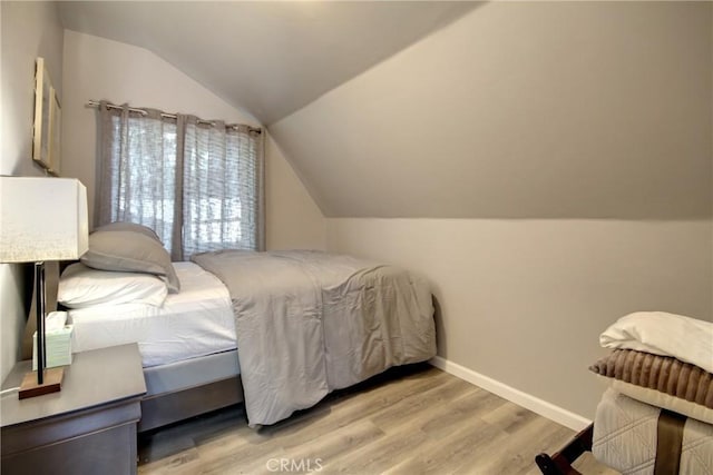 bedroom with vaulted ceiling and light hardwood / wood-style flooring