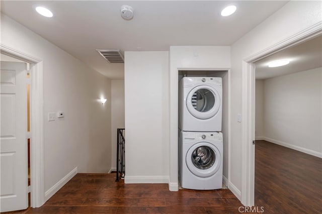 clothes washing area featuring stacked washing maching and dryer and dark wood-type flooring