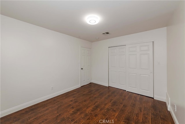 unfurnished bedroom featuring a closet and dark hardwood / wood-style floors