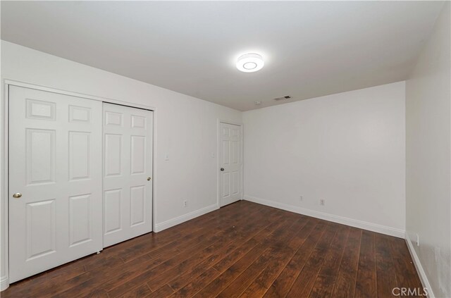 unfurnished bedroom featuring a closet and dark wood-type flooring