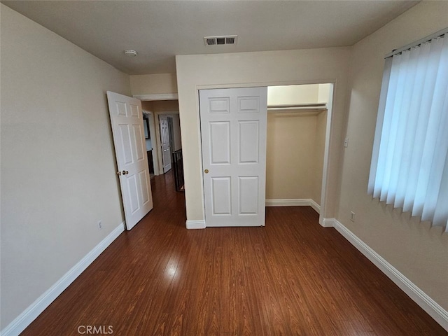 unfurnished bedroom featuring dark wood-type flooring and a closet