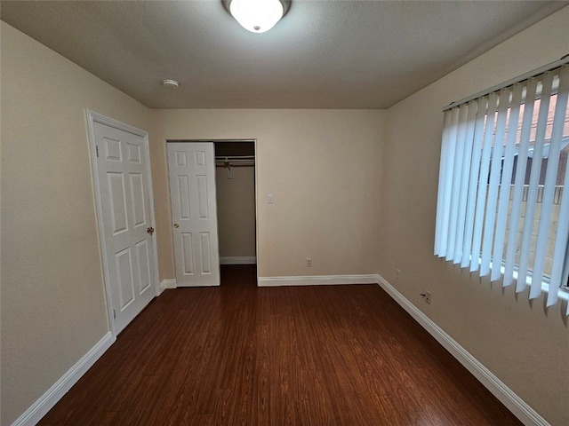 unfurnished bedroom with a closet and dark hardwood / wood-style floors