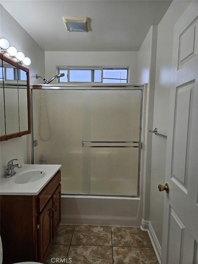 bathroom with vanity, combined bath / shower with glass door, a wealth of natural light, and tile patterned flooring