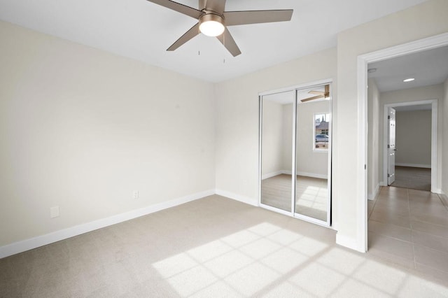 unfurnished bedroom featuring ceiling fan, light colored carpet, and a closet