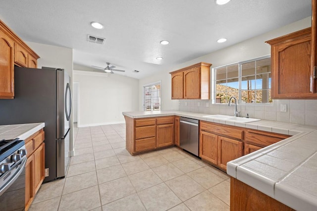 kitchen featuring kitchen peninsula, appliances with stainless steel finishes, tile countertops, and plenty of natural light