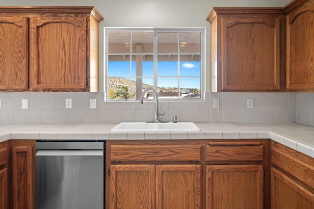 kitchen featuring decorative backsplash, sink, stainless steel dishwasher, and tile counters