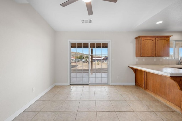 kitchen featuring light tile patterned flooring, tile countertops, a wealth of natural light, and ceiling fan