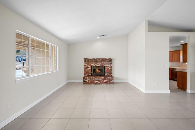 unfurnished living room with lofted ceiling, light tile patterned floors, and a brick fireplace