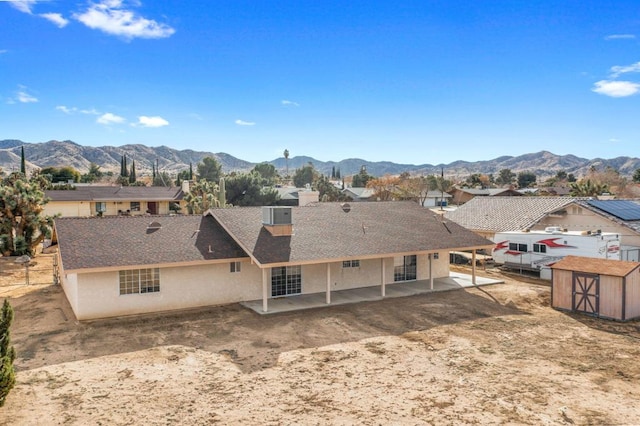 back of property featuring a mountain view, a patio, and a storage shed