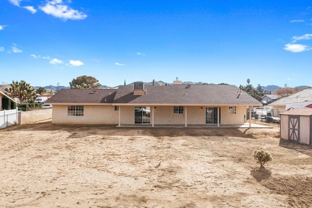 back of property with central AC unit and a storage unit