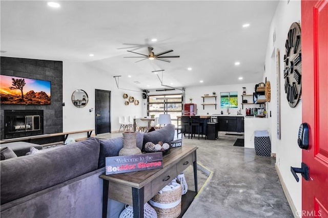 living room featuring sink, a tile fireplace, ceiling fan, and vaulted ceiling