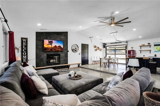 living room featuring ceiling fan, concrete floors, lofted ceiling, and a fireplace