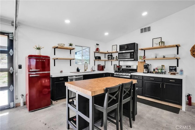 kitchen with a center island, stainless steel appliances, a breakfast bar, lofted ceiling, and wood counters