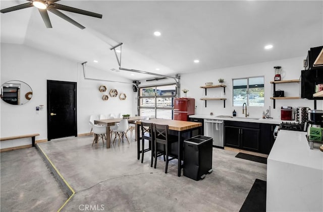 kitchen featuring wooden counters, stainless steel dishwasher, lofted ceiling, and a kitchen island