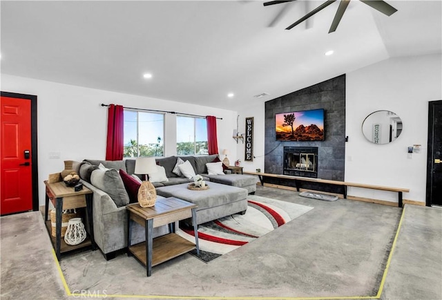 living room featuring ceiling fan, a tiled fireplace, and vaulted ceiling