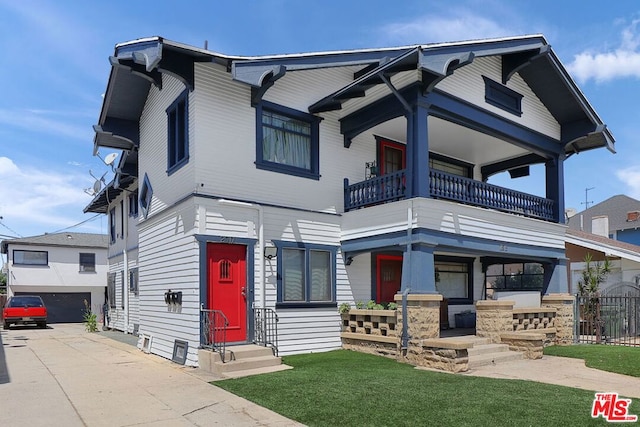 view of front facade featuring a balcony, a front yard, and a garage