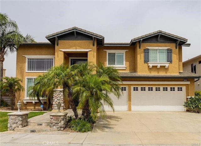 view of front of property with a tile roof, driveway, an attached garage, and stucco siding