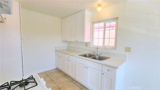 kitchen with white cabinetry, sink, light tile patterned floors, and range