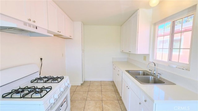 kitchen with white cabinetry, sink, light tile patterned floors, and white gas range oven