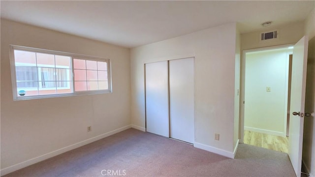 unfurnished bedroom with light carpet and a closet