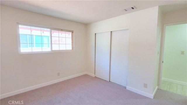 unfurnished bedroom featuring light carpet and a closet