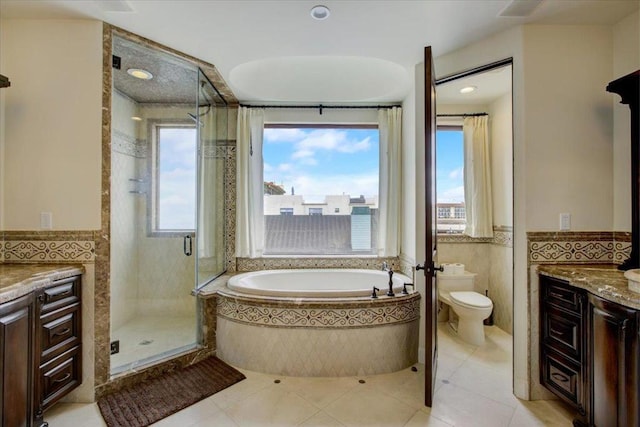 full bathroom featuring vanity, toilet, tile walls, and independent shower and bath