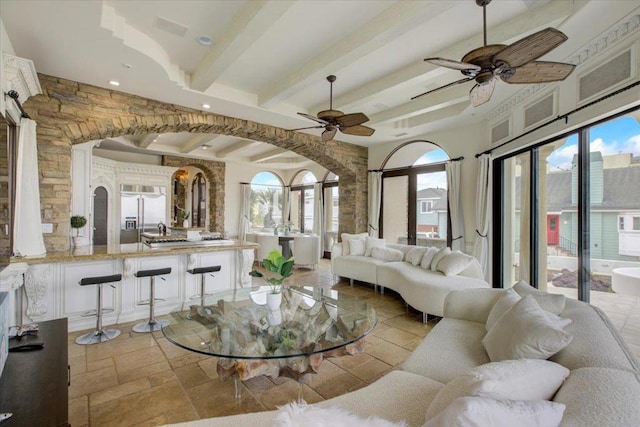 living room with beam ceiling, a healthy amount of sunlight, and ceiling fan