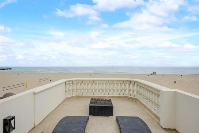 view of patio / terrace with a water view and a beach view