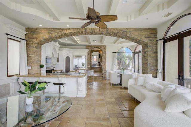 living room featuring ceiling fan, beamed ceiling, and a wealth of natural light