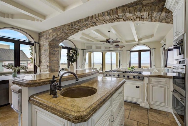 kitchen with sink, an island with sink, and white cabinets