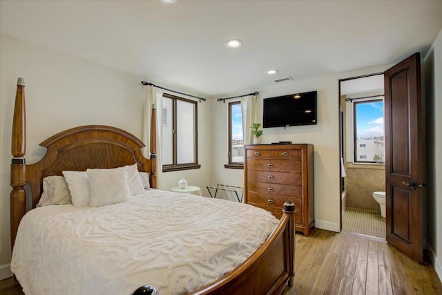 bedroom with light hardwood / wood-style flooring, ensuite bathroom, and multiple windows