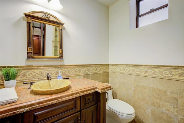 bathroom featuring vanity, toilet, and tile walls