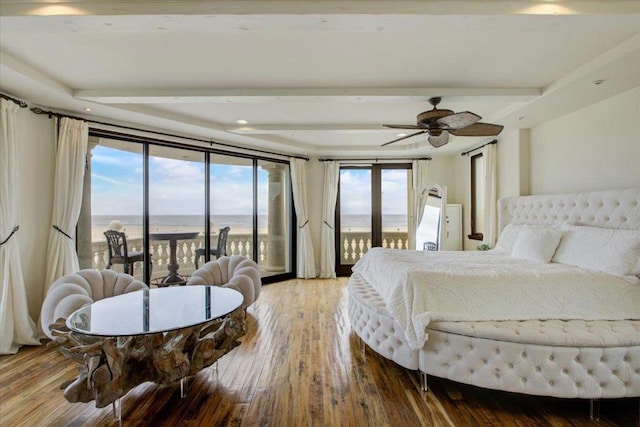 bedroom featuring access to outside, multiple windows, hardwood / wood-style floors, and a water view