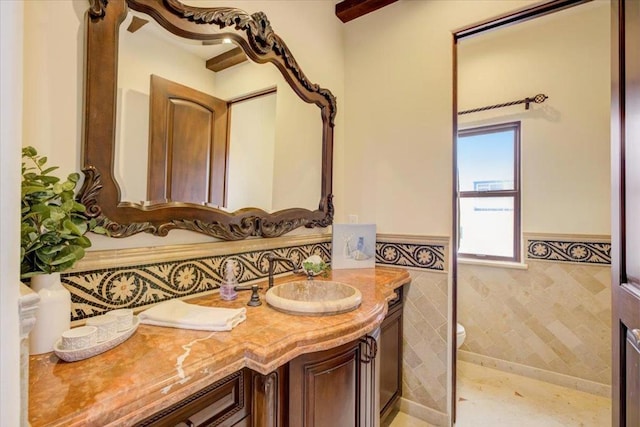 bathroom with vanity, toilet, and tile walls