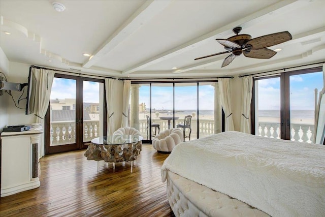 bedroom with multiple windows, a water view, and dark hardwood / wood-style flooring