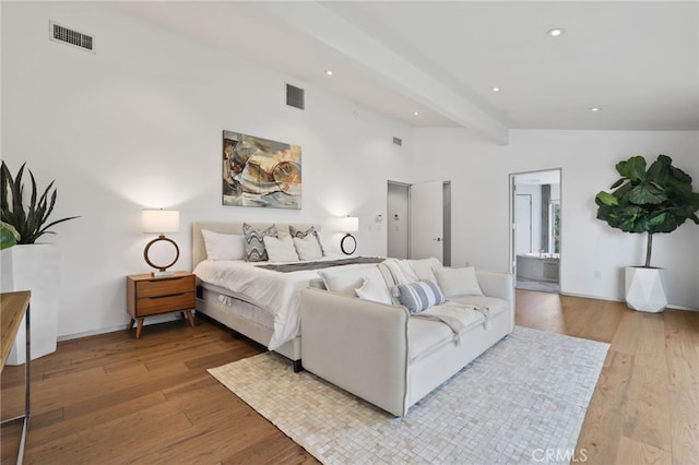 bedroom with ensuite bath, lofted ceiling with beams, and light wood-type flooring