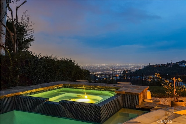 pool at dusk featuring an in ground hot tub