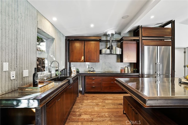 kitchen with wall chimney exhaust hood, sink, stainless steel fridge, light hardwood / wood-style flooring, and beam ceiling