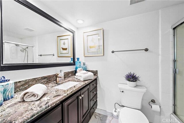 bathroom with vanity, a shower with shower door, and toilet